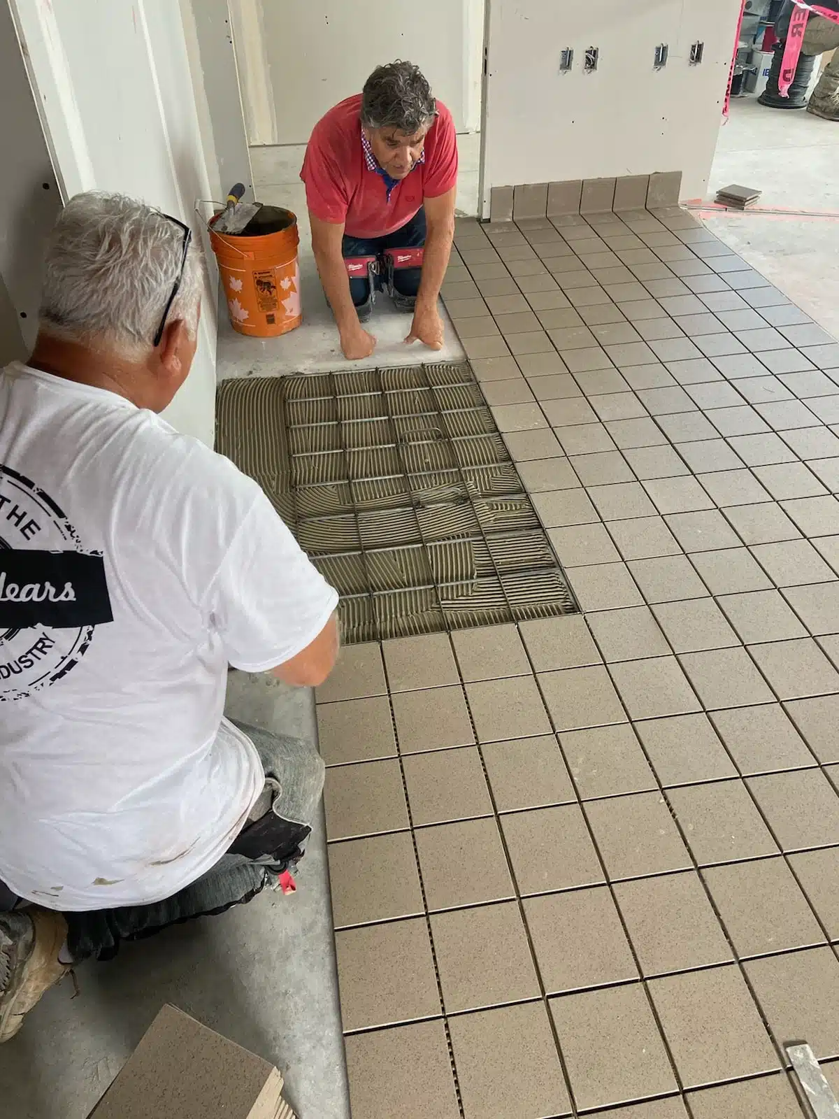 Cutting and installing floor tiles on a construction site, demonstrating craftsmanship and tile layout planning.