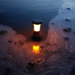 Warm LED lantern illuminating icy surface with cracks and rocks, outdoor winter winterlighting, NIS Tools branding, safety gear, camping essentials, winter outdoor equipment, emergency light, rugged outdoor tools, winter camping gear, portable LED lantern, reliable outdoor lighting, NIS Tools outdoor gear, ice fishing leds, essential winter accessories, outdoor adventure gear, durable winter lantern, compact camping light, weather-resistant outdoor tools, winter survival gear, outdoor lighting solutions, rugged winter product, NIS Tools outdoor essentials, winter hiking gear.