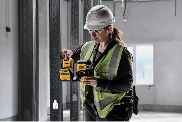DeWalt cordless power tools being used by a female construction worker at a building site; focused on safety gear and industrial equipment.