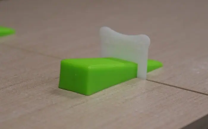 Green window cleaning squeegee with white scrubber on wooden surface.