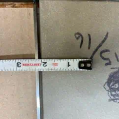 Measuring tape stretched across tiles showing measurement in inches, highlighting precision and accuracy in tile installation and grading.