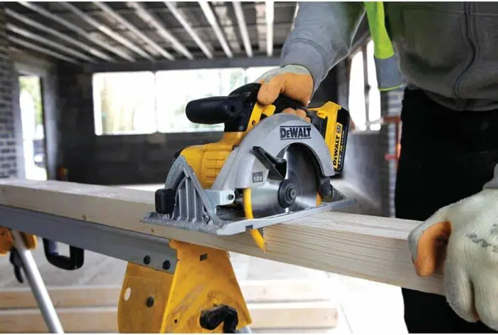 Powerful DEWALT circular saw cutting through wood at a construction site. Skilled worker operating tool for precise carpentry work. Indoor construction with natural lighting and unfinished structure.