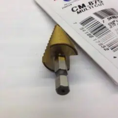 Precision machining tool with a metallic gold finish and hexagonal shank, positioned on white paper beside a label with barcode and product details.