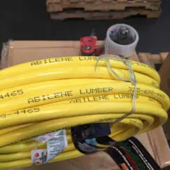 High voltage yellow electrical cables labeled "Abilene Lumber" coiled and secured with a metal wire, with electrical connectors and equipment visible on a wooden pallet for industrial wiring or power distribution projects.