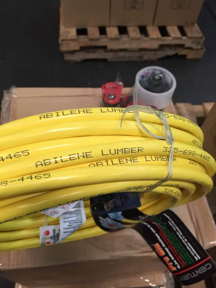 High voltage yellow electrical cables labeled "Abilene Lumber" coiled and secured with a metal wire, with electrical connectors and equipment visible on a wooden pallet for industrial wiring or power distribution projects.