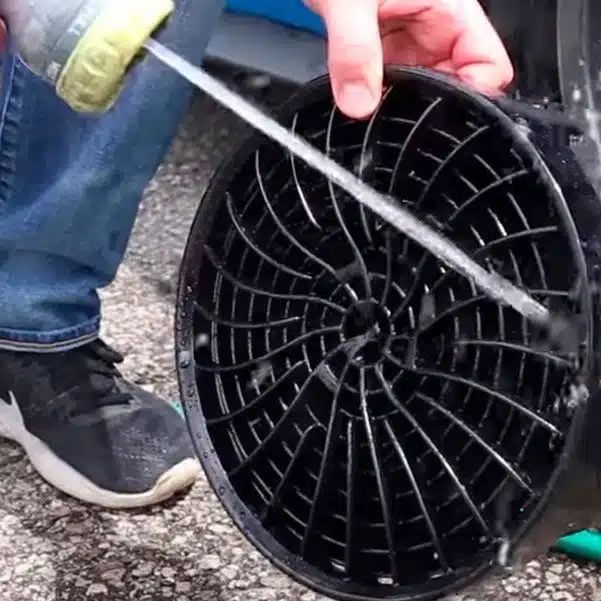 Drain cleaning tool being rinsed with water from a hose, outdoor cleaning, maintenance equipment for clogged drains.