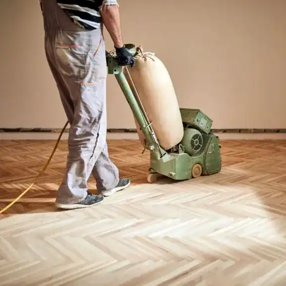 Experienced professional using NIS floor sanding equipment to restore hardwood floors, ensuring high-quality results and smooth, polished finishes for residential or commercial spaces.