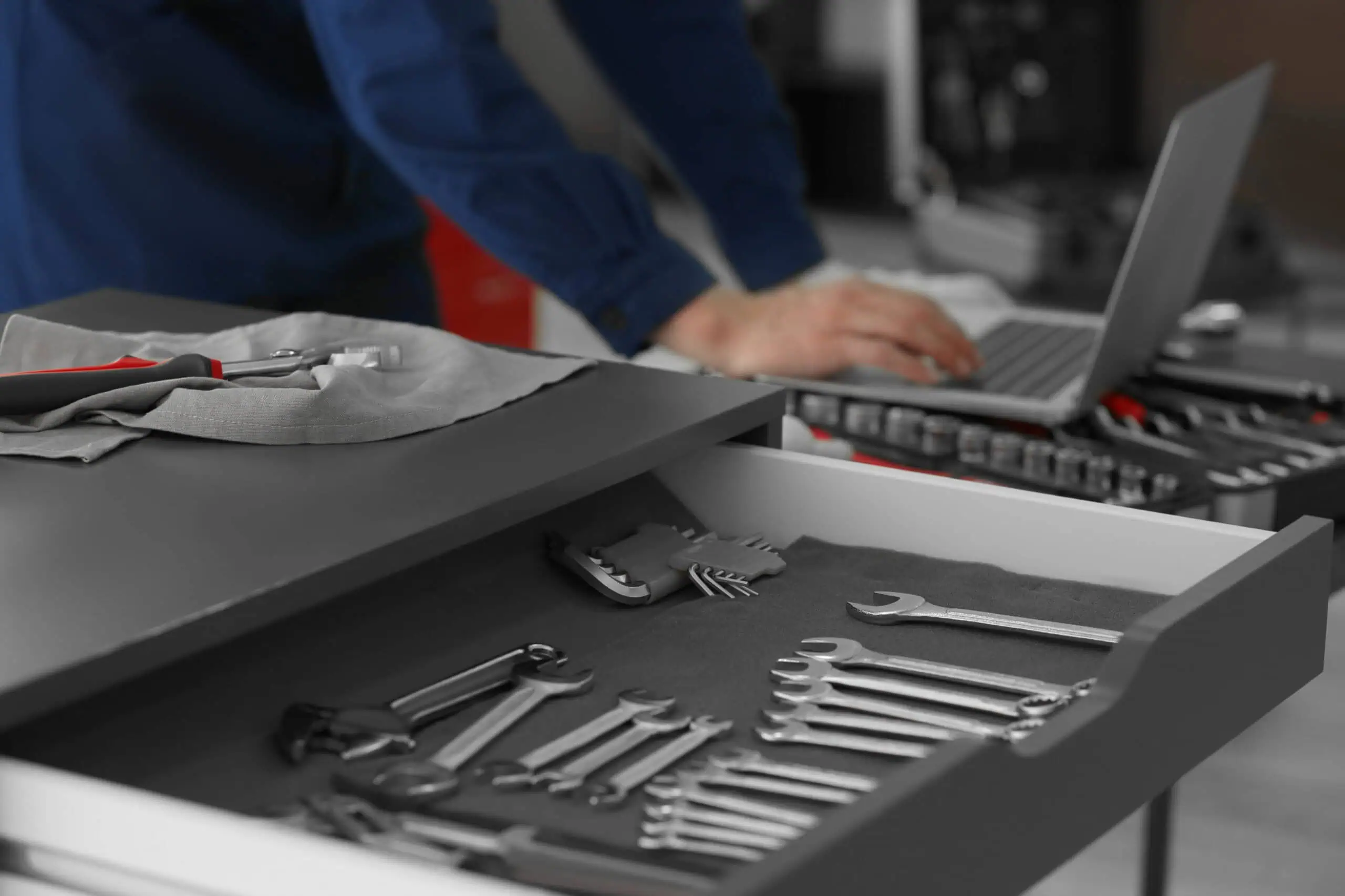 Mechanic working with tools and laptop in workshop